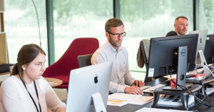 Three people at their desks working in an office. 